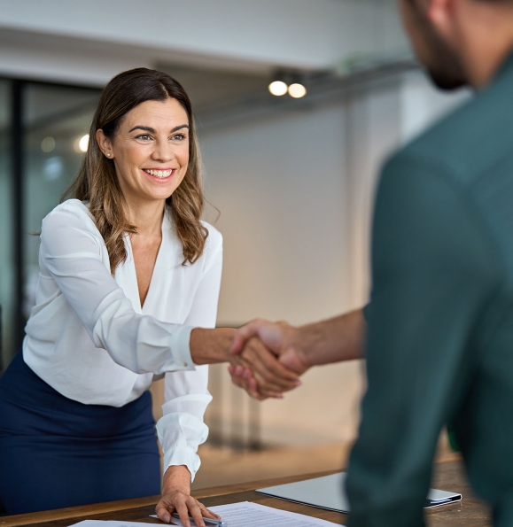 Business handshake concept. Happy middle aged professional woman manager and male client or partner shaking hand expressing trust in b2b partnership at meeting in corporate office. Hiring, onboarding.